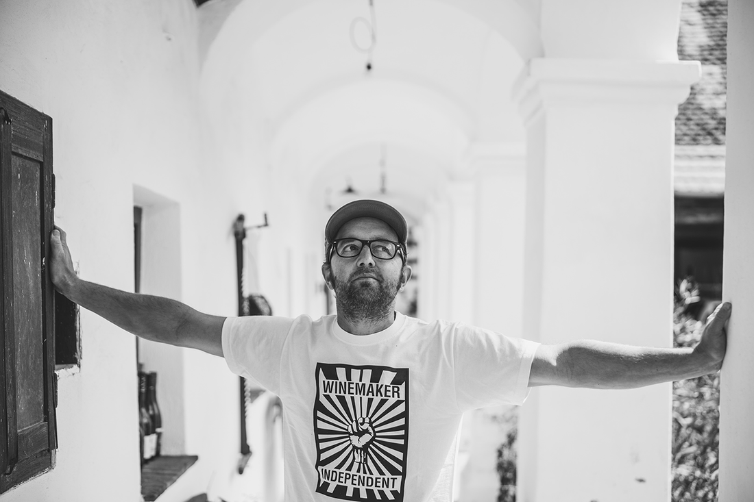 Mann mit Brille und Cap trägt Winemaker Independent T-Shirt, steht in heller Arkadengang